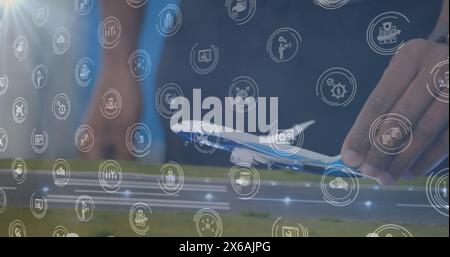 Image of digital icons over mid section of a woman flying a airplane model at office Stock Photo