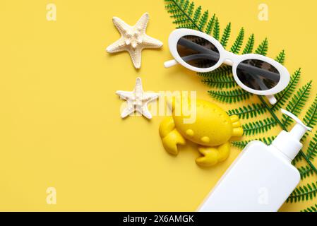 Top view of sunglasses,starfishs,beach toy and sunscreen and with copy space for text over yellow background. Summer holiday concept Stock Photo