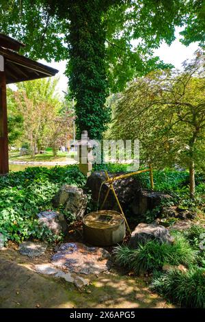 A bamboo fountain, pump and stone lantern. At the traditional Japanese Garden public park in Tashlent, Uzbekistan. Stock Photo