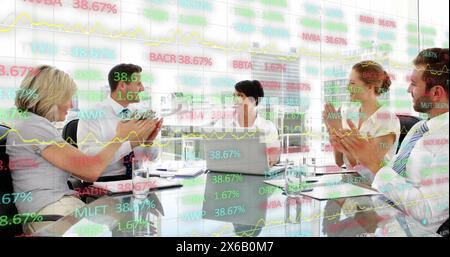 Image of trading board over diverse coworkers discussing reports and clapping in office Stock Photo