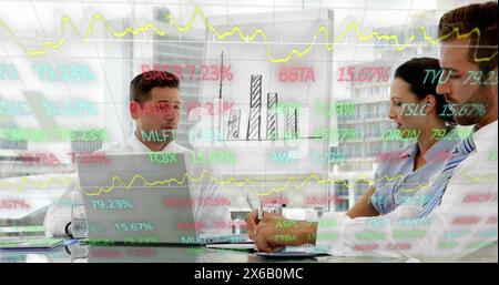 Image of trading board and graphs over diverse coworkers discussing reports in office Stock Photo
