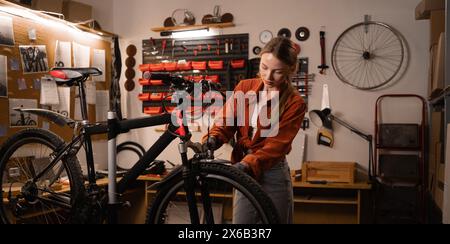 Young handywoman with bicycle during a repairman in home workshop or garage. DIY and hobby concept Stock Photo