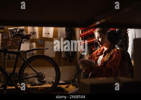Portrait of woman wipes her hands with a rag while working at a repair shop, bicycle maintenance. Stock Photo