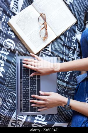 Above, laptop and typing with textbook for student in college or university in studying for exam or test. Top view, computer and hands for writing Stock Photo