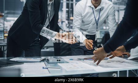 Close Up of a Team of Automotive Engineers Working in Office at Car Factory. Industrial Designer Talks About Electric Engine Parts with Colleagues, Discussing Different Technological Applications. Stock Photo