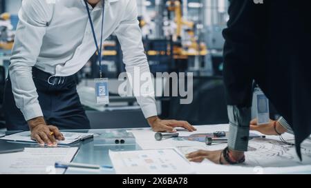 Two Young Automotive Engineers Working in Office at Car Factory. Industrial Designer and Colleague Discussing Different Applications of a Metal Pinion Gear in Personal Mobility Vehicles. Stock Photo