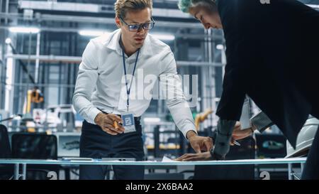 Two Young Automotive Engineers Working in Office at Car Factory. Industrial Designer and Colleague Discussing Different Applications of a Metal Pinion Gear in Personal Mobility Vehicles. Stock Photo