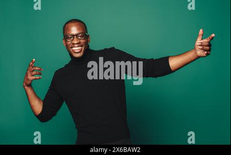 Confident and carefree young man in trendy casual clothing, smiling and posing with stylish glasses. Green background accentuates his happy and fashio Stock Photo