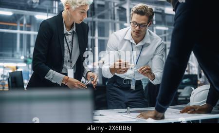 Young Diverse Team of Automotive Engineers Working in Office at Car Factory. Industrial Designer Talks About Electric Engine Parts with Colleagues, Discussing Different Technological Applications. Stock Photo