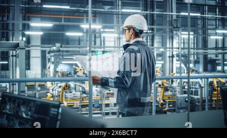 Engineer in Uniform and Hard Hat Looking at a Technical Blueprint at Work in an Office at Car Assembly Plant. Industrial Specialist Working on Vehicle Parts in Technological Development Facility. Stock Photo