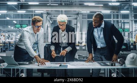 Young Diverse Team of Automotive Engineers Working in Office at Car Factory. Industrial Designer Talks About Electric Engine Parts with Colleagues, Discussing Technical Blueprint for Mobility Project. Stock Photo