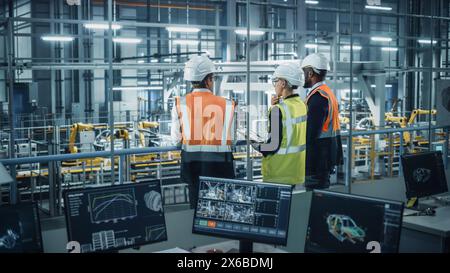 Young Diverse Team of Automotive Engineers Working in Office at Car Factory. Industrial Designer Talks About Electric Engine Parts with Colleagues, Discussing Different Technological Applications. Stock Photo