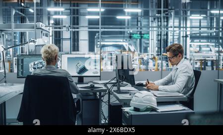 Team of Automotive Engineers Working on Desktop Computers in Modern Office at Car Assembly Plant. Industrial Product Designer Developing Electric Engine Parts with Colleagues at Vehicle Factory. Stock Photo