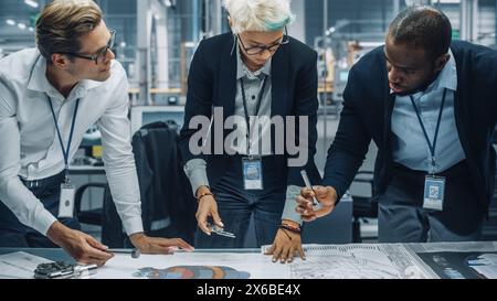 Young Diverse Team of Automotive Engineers Working in Office at Car Factory. Industrial Designer Talks About Electric Engine Parts with Colleagues, Discussing Technical Blueprint for New Vehicle. Stock Photo