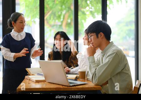 College students attentively listening to mature professor in the classroom Stock Photo
