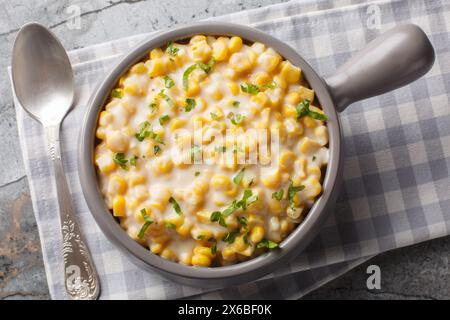 Creamy corn with cream, milk and grated parmesan closeup on the bowl on the table. Horizontal top view from above Stock Photo