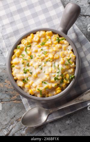 Creamed corn or cream-style sweet corn is a type of creamed vegetable dish closeup on the bowl on the table. Vertical top view from above Stock Photo