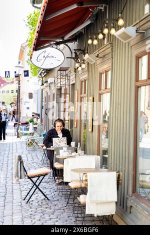 Woman working on laptop outside Caféva cafe on Haga Nygata, Haga District, Gothenburg, Sweden Stock Photo