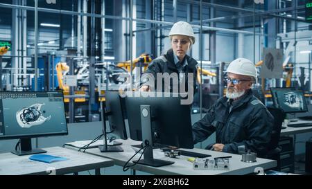 Car Factory Office: Female Manager Talks to Male Automotive Engineer Working on Computer. Automated Robot Arm Assembly Line Manufacturing Electric Vehicles. Technicians Monitoring Conveyor Production Stock Photo