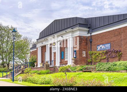 Art Gallery building set in a park with columns at the entrance. Benches are outside and a flower bed is in the foreground. Stock Photo