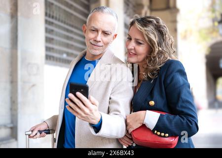 Happy friends or couples using an app on the smartphone outdoors. Stock Photo