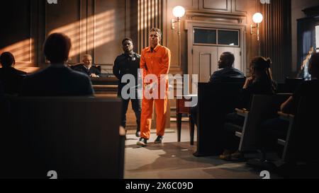 Cinematic Court of Law and Justice Trial Proceedings: Portrait of Accused Sad Male Criminal in Orange Jumpsuit Led Away by Security Guard in Front of Judge and Jury. Sentenced to Serve Jail Time. Stock Photo