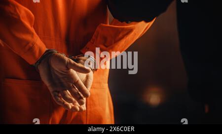 Cinematic Close Up Footage of a Handcuffed Convict at a Law and Justice Court Trial. Handcuffs on Accused Criminal in Orange Jail Jumpsuit. Law Offender Sentenced to Serve Jail Time. Stock Photo