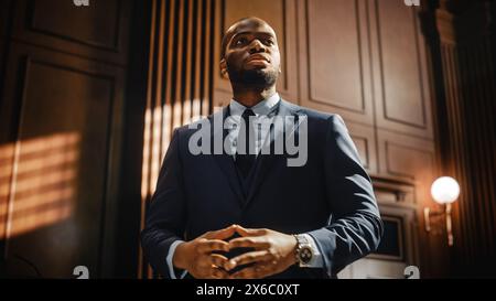 Court of Law Trial in Session: Portrait of Charismatic Male Public Defender Making Touching, Passionate Speech to Judge and Jury. Attorney Lawyer Protecting Client, Cross Examining Witnesses Stock Photo