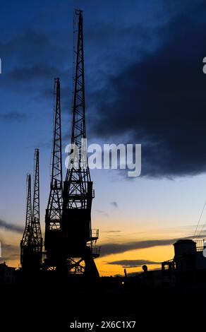 Cranes in The dock at Harbourside area in Bristol at sunset Stock Photo
