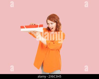 Portrait of excited happy red bob hair caucasian woman looking inside opening gift box. What a great surprise concept idea image. People lifestyle. Stock Photo