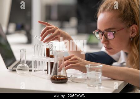 Caucasian woman in a medical gown doing laboratory experiments.  Stock Photo