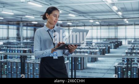 Data Center Engineer Using Laptop Computer. Server Farm Cloud Computing Specialist Facility with Multiethnic Female System Administrator Working with Data Protection Network for Cyber Security. Stock Photo