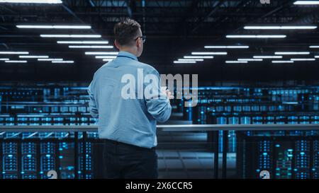 Data Center Engineer Using Laptop Computer. Server Farm Cloud Computing Specialist Facility with Adult Male System Administrator Working with Data Protection Network for Cyber Security. Stock Photo