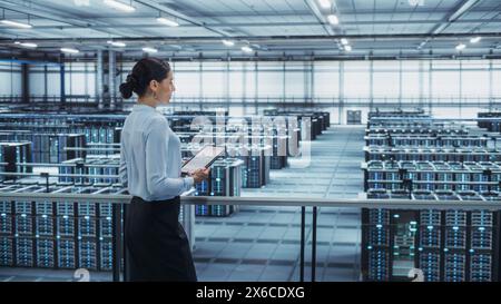 Data Center Engineer Using Tablet Computer. Server Farm Cloud Computing Specialist Facility with Multiethnic Female System Administrator Working with Data Protection Network for Cyber Security. Stock Photo