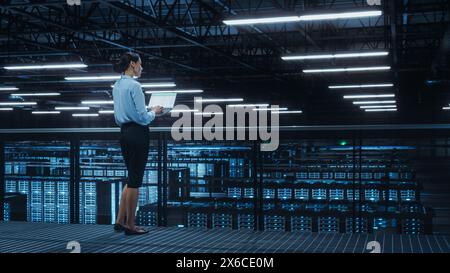 Data Center Engineer Using Laptop Computer. Server Farm Cloud Computing Specialist Facility with Multiethnic Female System Administrator Working with Data Protection Network for Cyber Security. Stock Photo