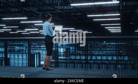 Data Center Engineer Using Laptop Computer. Server Farm Cloud Computing Specialist Facility with Female System Administrator Working with Data Protection Network for Cyber Security. Stock Photo