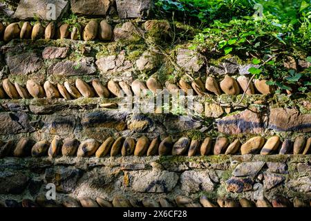 An old wall of stones and pebbles aligned with vegetation. Stock Photo
