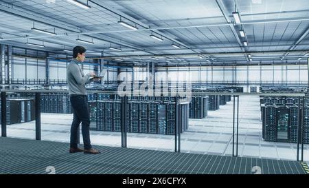 Data Center Engineer Using Laptop Computer. Server Farm Cloud Computing Specialist Facility with Asian Male System Administrator Working with Data Protection Network for Cyber Security. Stock Photo