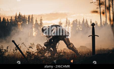 Dark Age Battlefield: Brutal Fight to Death of Two Armored Medieval Knights, Killing Enemy with Sword. Battle of Armed Warrior Soldiers. Dramatic Scene, Cinematic Smoke, Light in Historic Reenactment Stock Photo