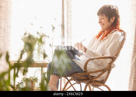 woman using tablet to draw working at home in a quiet space while having a video call red-haired woman smiling Stock Photo