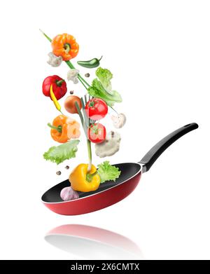 Frying pan and different vegetables in air on white background Stock Photo