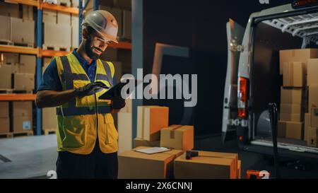 Outside of Logistics Retail Warehouse: Handsome Latin Manager Using Tablet Computer for Inventory. Delivery Service with Cardboard Boxes, Online Orders, E-Commerce. Evening Shot Stock Photo