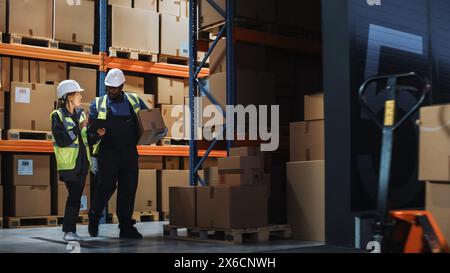 Outside of Logistics Distributions Warehouse: Inventory Manager Using Tablet Computer, talking to Worker with Cardboard Box Walking out of Warehouse. Online Orders, E-Commerce. Stock Photo