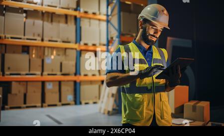 Outside of Logistics Retail Warehouse: Handsome Latin Manager Using Tablet Computer for Inventory. Delivery Service with Cardboard Boxes, Online Orders, E-Commerce. Evening Shot Stock Photo