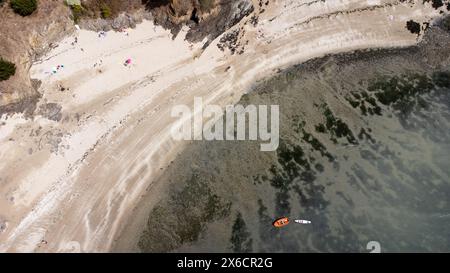 Aerial photo of the seascape with a small inflatable boat and a beach with tourists enjoying the summer sun at the Saint-Jacut de la Mer peninsula in Stock Photo