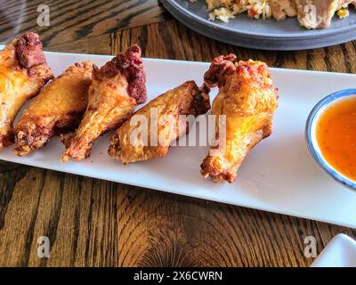 Crispy Fried Chicken with Spicy Sauce in Casual Dinner Setting, Eye-Level View Stock Photo