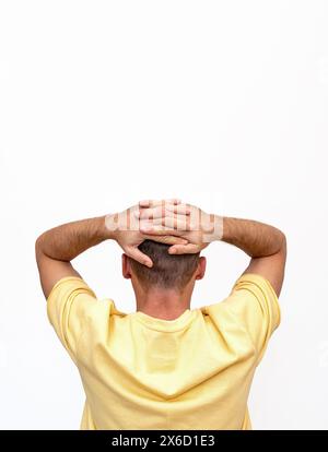Rear view isolated man in yellow t-shirt standing with his hands behind his head. Stock Photo