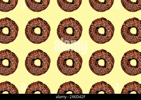 Creative pattern of chocolate donuts with holes on pastel yellow background. Stock Photo