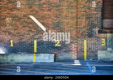 Weathered Brick Wall with Numbered Parking Spaces, Urban Texture Stock Photo