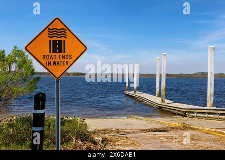 A caution sign warns that the road ends in the water at this boat ramp in the inlet waters near Charleston, South Carolina Stock Photo